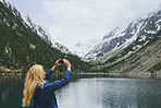 Travel adventure woman taking smart phone photograph on mountain lake enjoying beautiful nature landscape wanderlust