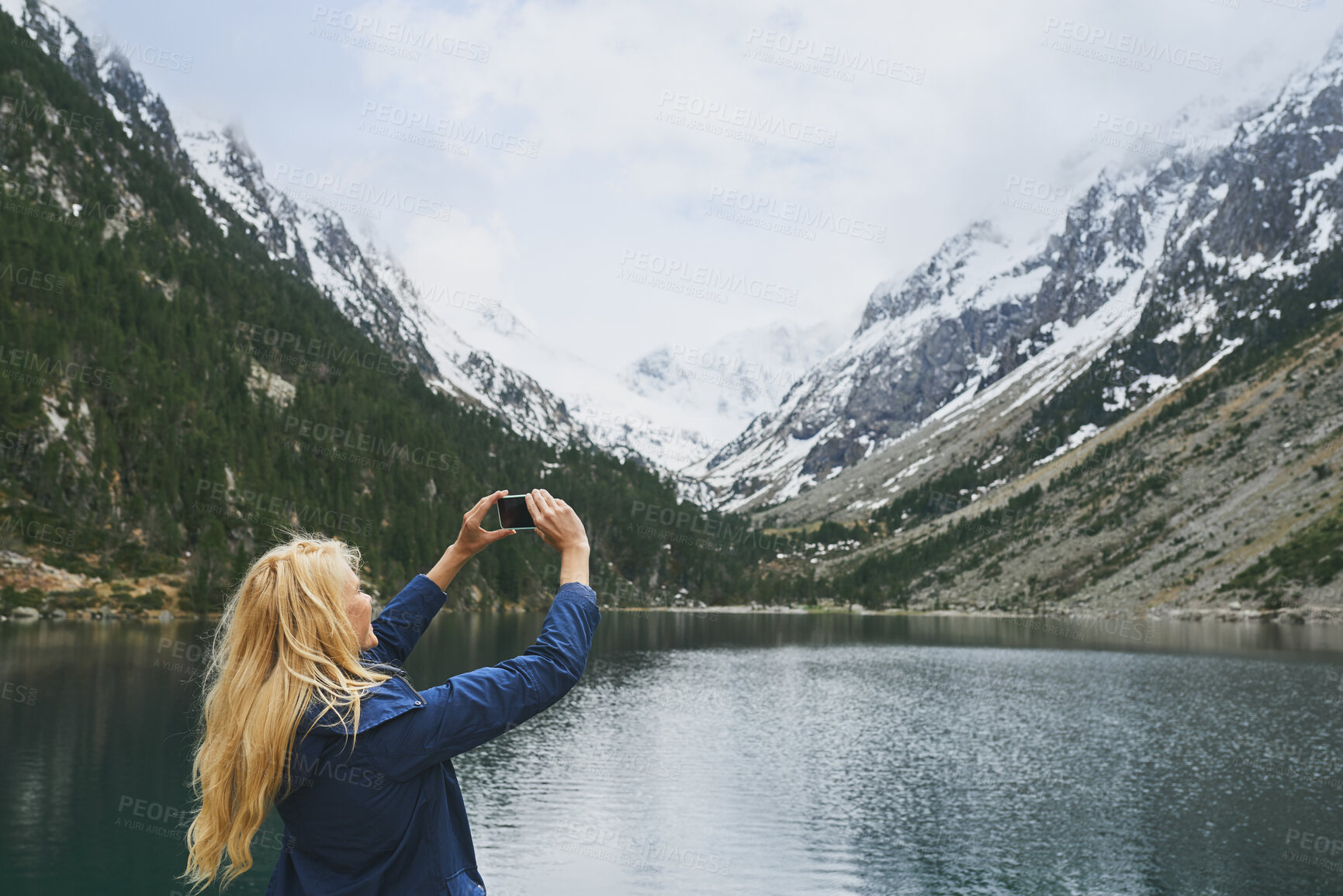 Buy stock photo Woman, lake and hiking with phone for photography, social media post or travel blog. Space, person and mobile for profile picture update, trekking scenery and river with mountain view in wilderness