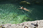 Adventure woman swim through surreal exotic paradise blue river on wanderlust travel vacation