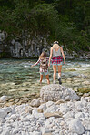 Brave friends cross river on travel adventure helping each other explore beautiful nature 