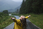 Happy young woman standing in rain with her arms outstretched rejoicing, celebrating and enjoying life