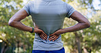 Outdoor, hands and runner with back pain for fitness, poor posture and overworked muscle for sprain. Park, sports injury and person with backache from training burnout, spine tension and discomfort