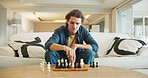 Man, chess and game on sofa with strategy, solution or problem solving in contest in living room. Male person, boardgame and idea with competition for thinking, knowledge or challenge in home