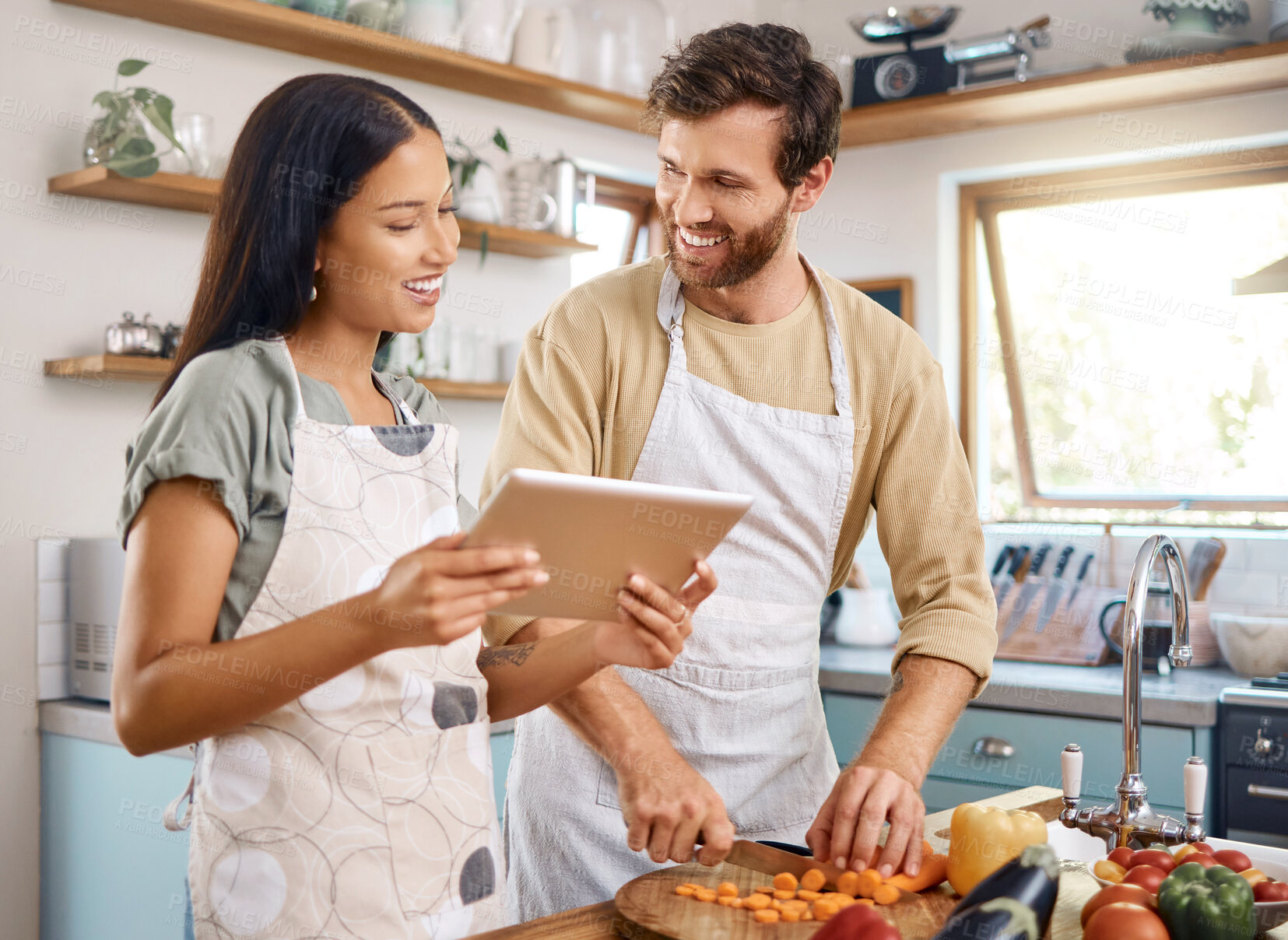 Buy stock photo Tablet, cooking or interracial couple in kitchen with smile, vegetable recipe or nutrition blog. Tech, man and woman at home for meal prep, food guide or cut organic carrots to help for vegan diet