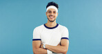 Arms crossed, portrait and tennis with man on studio space for health, retro sports or wellness. Confidence, fitness and smile with person on blue background for competition, game or hobby as player