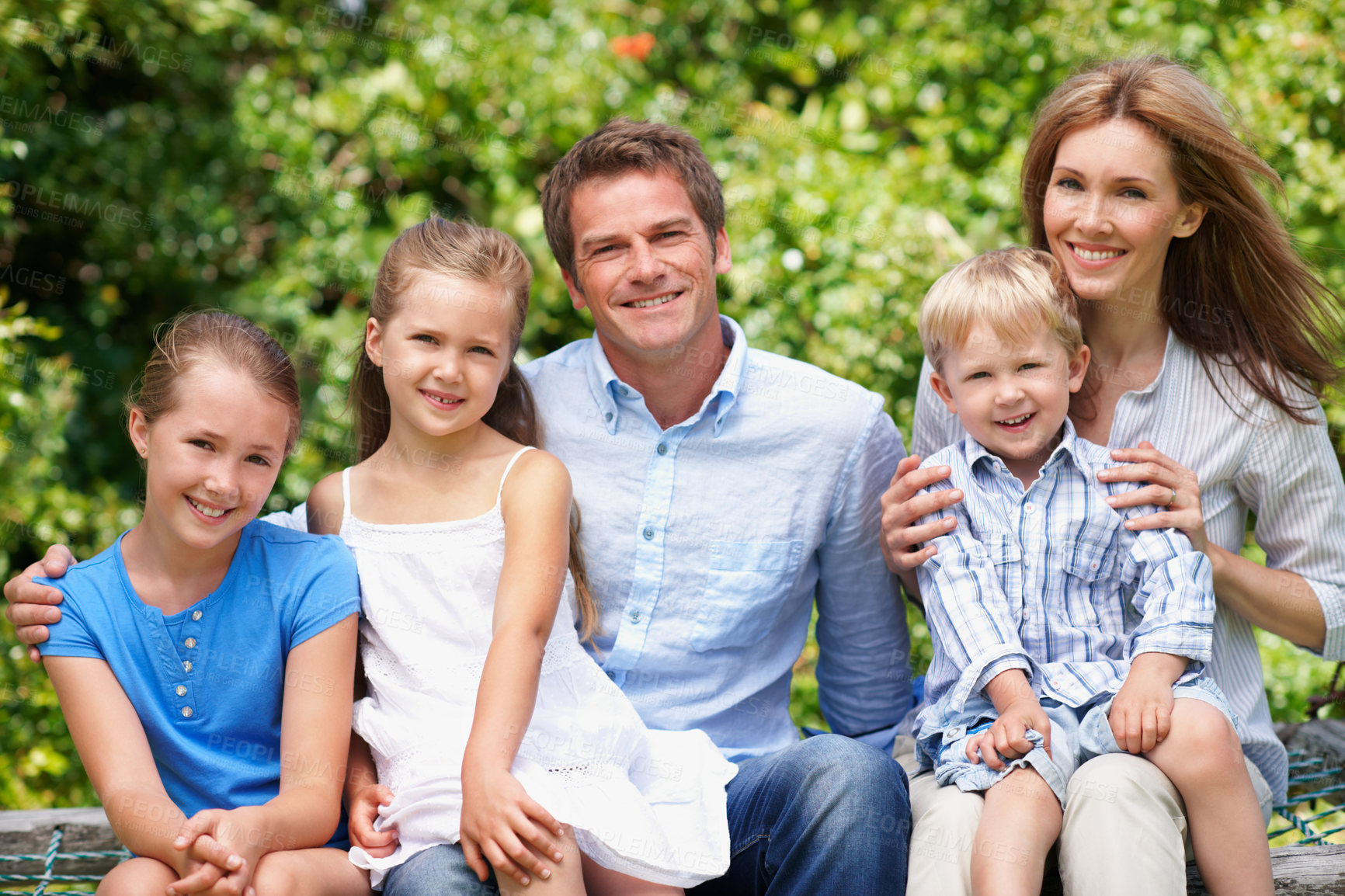 Buy stock photo Portrait, parents and relax with kids at park for love, affection and bonding on holiday trip. Happy, people and bench with children for support, family connection and vacation getaway in countryside