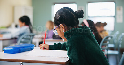 Buy stock photo Education, kid and writing test in classroom for assessment, quiz and development with student. School, girl child and book for exam at elementary, learning or study knowledge with course in lesson