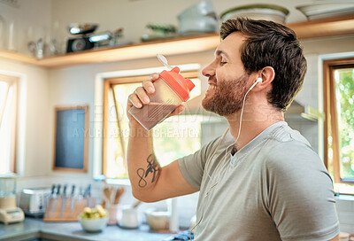 Buy stock photo Gut health, earphones or happy man in kitchen with protein shake, whey detox or smoothie for digestion. Wellness, person or audio tech in home with supplement drink, nutrition or smile for podcast