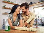 Loving young interracial couple cleaning their home. Young man and woman wearing gloves and using cleaning detergents while doing chores together at home.