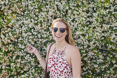 Buy stock photo Outdoor, laughing or woman with sunglasses for travel, eco tourism or sightseeing for spring vacation. Botanical park, holiday or happy person with shades by flower wall, space or nature growth