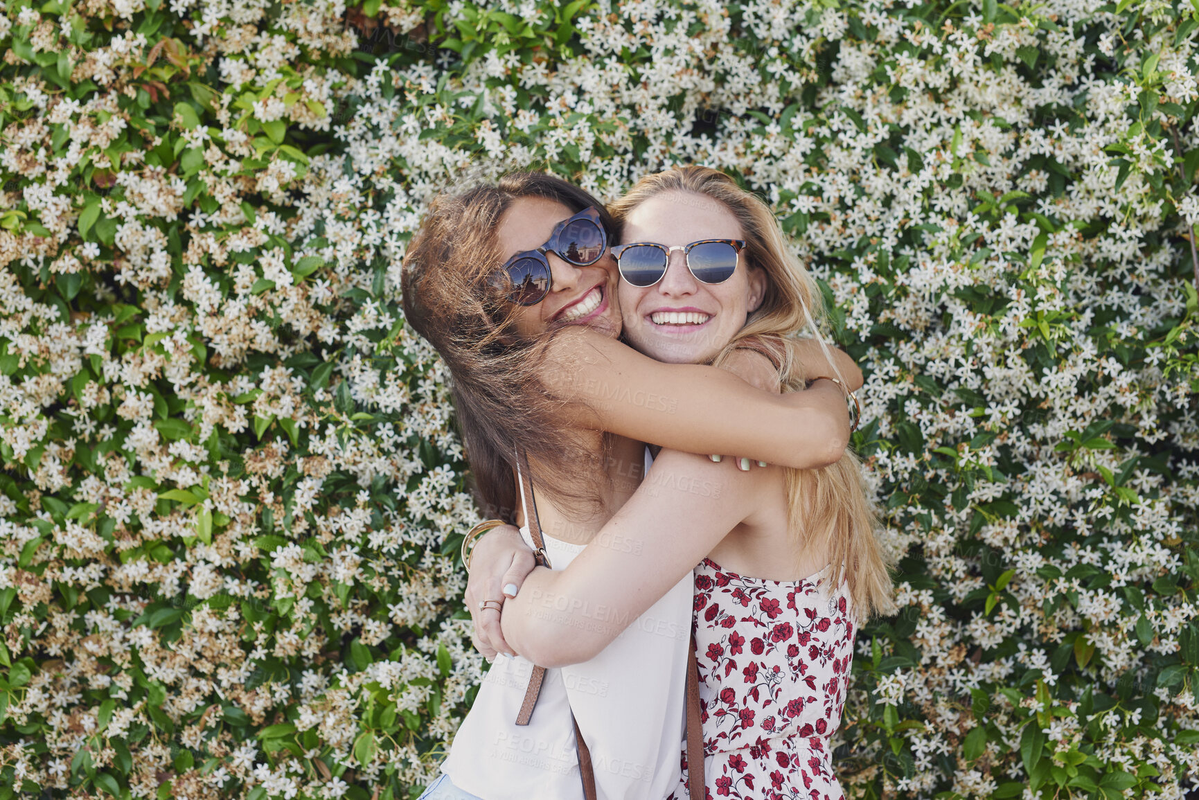 Buy stock photo Friends, hug and women with smile for reunion, flower background and bonding on weekend or together. Happy people, portrait and laughing with sunglasses on break, hangout and affection with embrace
