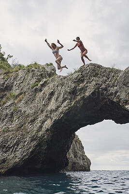 Buy stock photo Cliff, friends and woman jumping in ocean together for holiday, travel or vacation activity. Courage, leap and rocks with people plunge into sea for action, adrenaline or bonding on summer morning