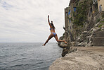 Beautiful girl  jumping into ocean having excitement freedom fun action healthy travel vacation adventure