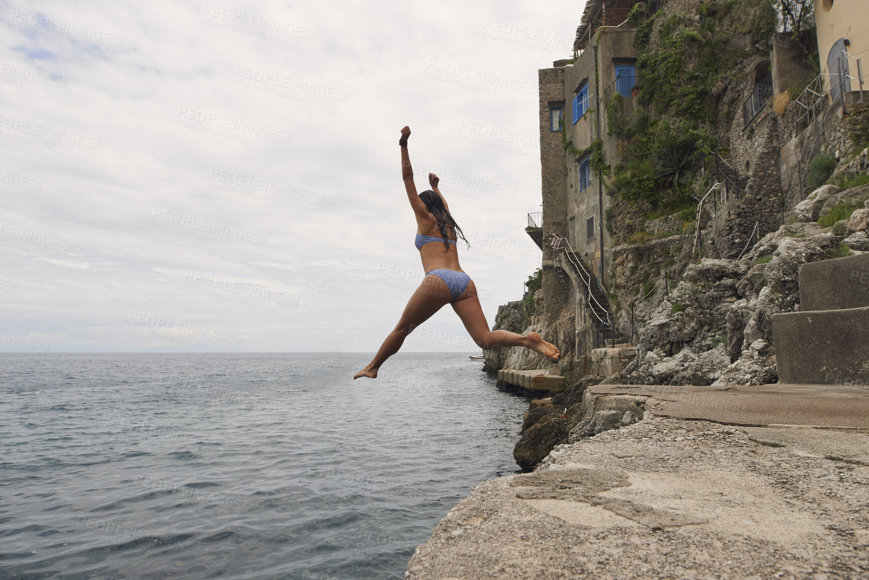 Buy stock photo Back, travel and woman jumping in ocean with adrenaline, adventure and diving on holiday. Thrill, leap and female person on coastal ledge with freedom, sea water and tropical vacation for summer trip