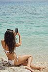 Beautiful woman taking photos with smart phone technology on paradise beach destination summer wanderlust vacation