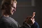 Attractive man using smart phone technology at home browing social media in internet network