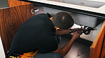 Repair, sink and man with wrench in kitchen for drainage system maintenance or plumbing skills in house. Handyman, fixing and pipe improvement with equipment, installation and leak prevention in home