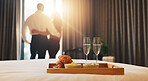 Champagne, breakfast and couple in hotel with room service for anniversary holiday, getaway or vacation. Curtains, sparkling wine and back of people by window for view with morning meal on trip.