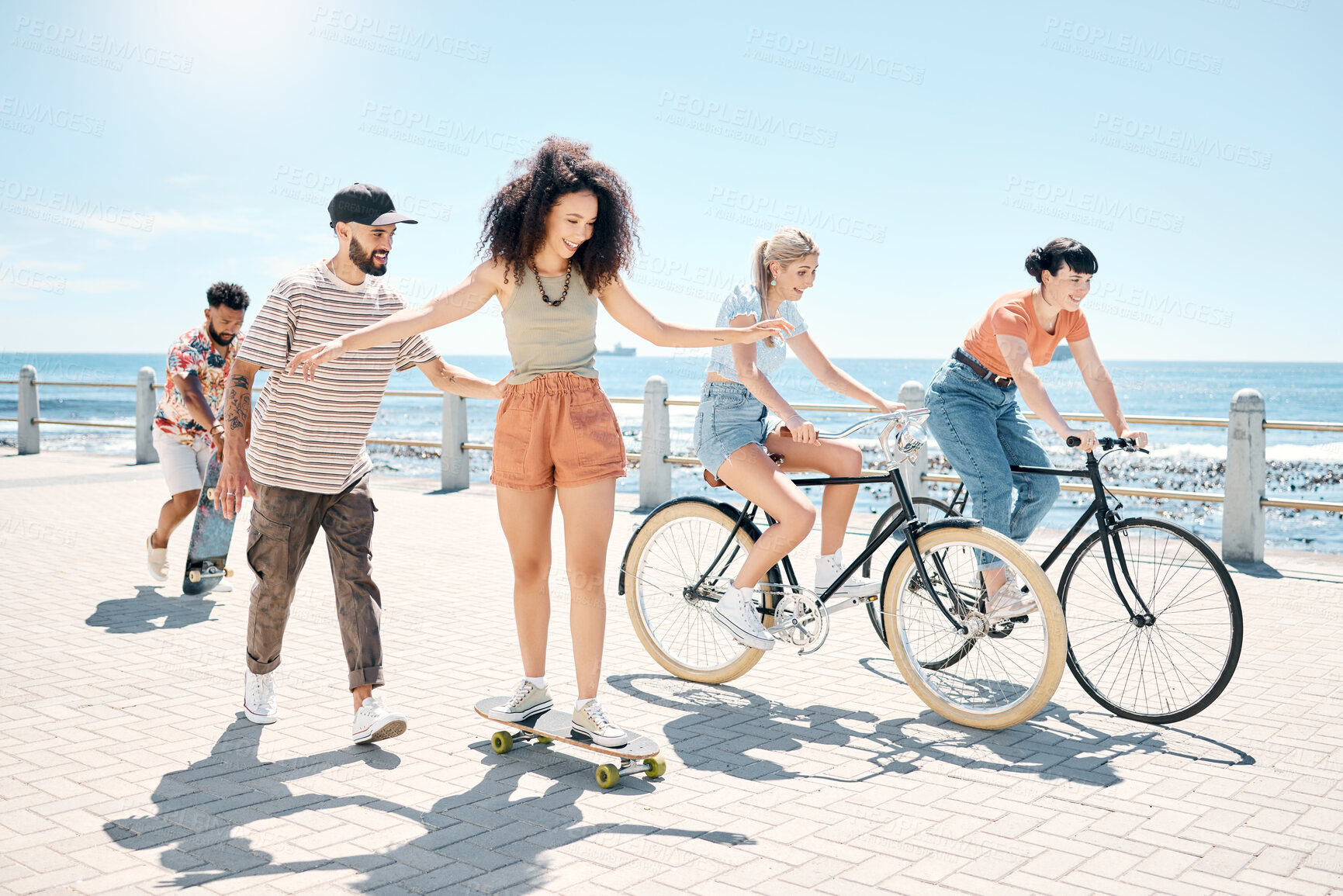 Buy stock photo Reunion, summer or friends at beach with fun, seaside skating or bonding in weekend gathering. Happy, space or people on promenade with bicycles, good time or get together with outdoor activity.