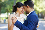 Bride and groom dancing outside. Mixed race newlyweds enjoying romantic moments on their wedding day. Happy young romantic couple sharing a dance in nature