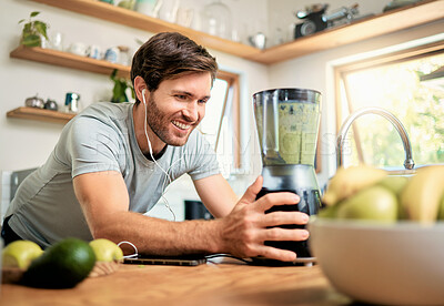 Buy stock photo Earphones, man and happy with blender in home for green smoothie, healthy diet or detox shake. Streaming music, person and smile with meal prep in kitchen for breakfast drink, nutrition or gut health