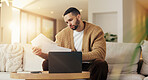 Reading, paperwork and man with laptop in lounge, financial planning and checking home loan payment. Review, documents and person with tech for mortgage info, bills and expense statement in house