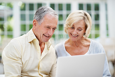 Buy stock photo A delighted senior couple using a laptop while relaxing in their lounge