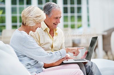 Buy stock photo A pretty senior woman showing her husband something on the laptop screen