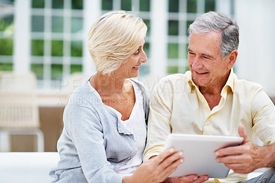 Buy stock photo A senior couple using a digital tablet from the comfort of home