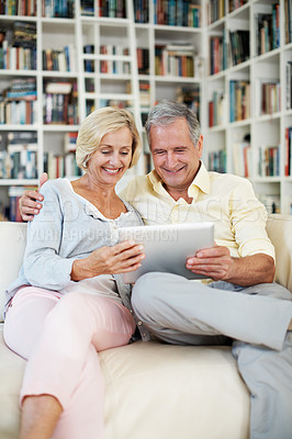 Buy stock photo A senior couple reading an ebook together in their study at home