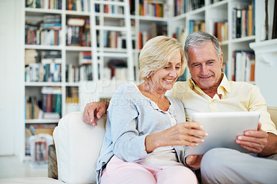 Buy stock photo A senior couple reading an ebook together in their study at home