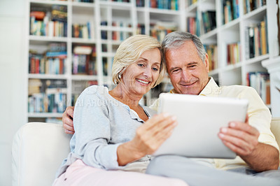 Buy stock photo A senior couple reading an ebook together in their study at home