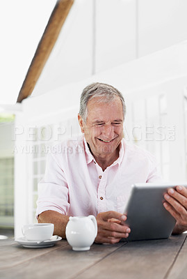 Buy stock photo A smiling senior man sitting outside his home working on a digital tablet 