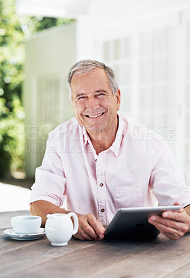 Buy stock photo A smiling senior man holding a digital tablet while sitting outside with a cup of coffee - portrait