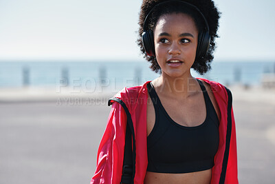 Buy stock photo Fitness, music and black woman with headphones on beach promenade for outdoor workout or sound app. Active, female person or runner listening with audio streaming app for exercise on ocean coast