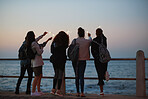 Group of friends waving sparklers celebrating new years eve by the sea enjoying holiday celebration at sunset