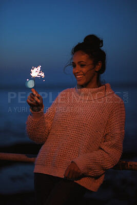 Buy stock photo Smile, woman and sparkler at beach for celebration, new year and travel on vacation at night. Happy, person and fireworks at promenade party by ocean, festive season and glow on holiday outdoor