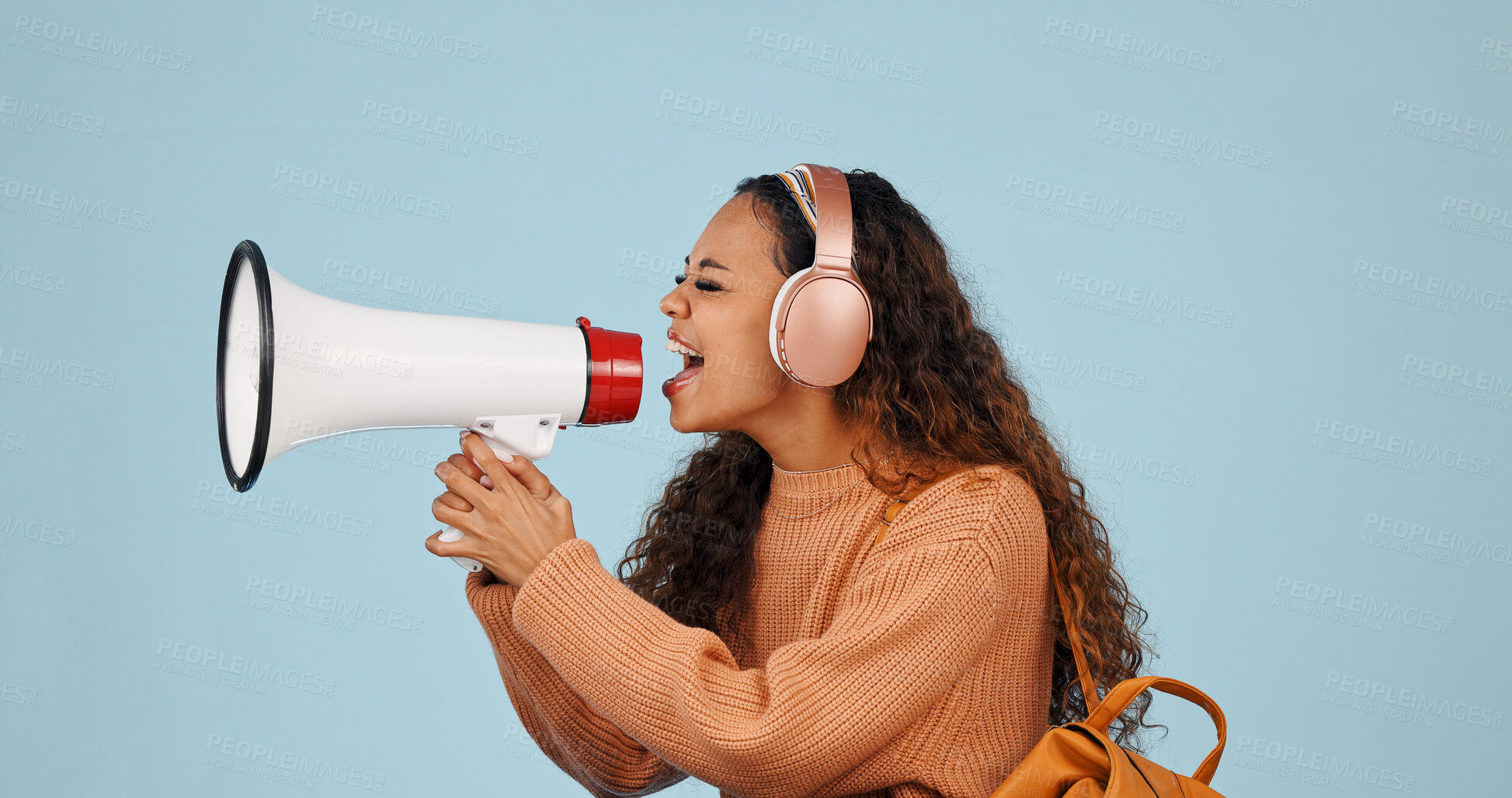 Buy stock photo Headphones, megaphone and woman in studio with protest, march or speech on politics for justice. Audio tech, loudspeaker and female person with bullhorn for announcement of news by blue background,