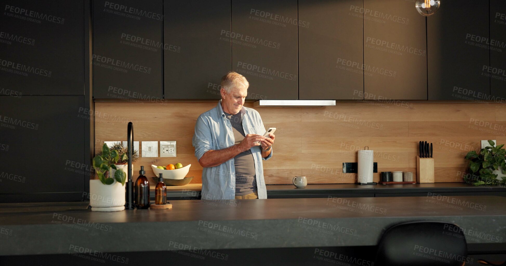 Buy stock photo Message, smile or old man in kitchen with phone, reading news or post update on social media. Happy, space or senior person in home with tech, headline search or chat notification on digital app.