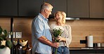 Love, flowers and old couple in home for support, comfort or bonding together in kitchen. Smile, commitment and elderly man with woman for gift with marriage, anniversary and bouquet in apartment