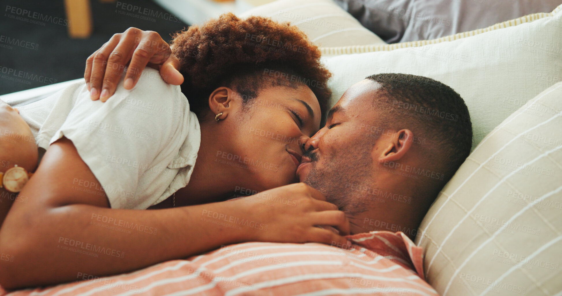 Buy stock photo Affection, kiss and relax with black couple in bed at apartment together for bonding, connection or rest. Love, morning and wake up with happy people in bedroom of home for break, holiday or romance