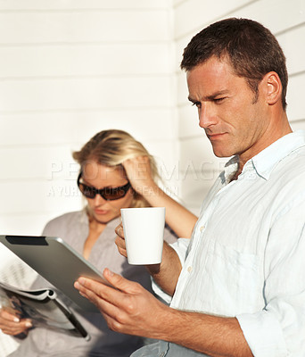 Buy stock photo Serious, couple and man on patio with tablet, social media and browsing website for weekend. People, coffee and online news at home with tech, calm morning and reading ebook for bonding together