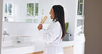 Happy woman, singing and mirror with hairbrush for hair care, morning routine and fun with song in bathroom. Bamboo brush, female person and grooming in home for beauty, karaoke and getting ready