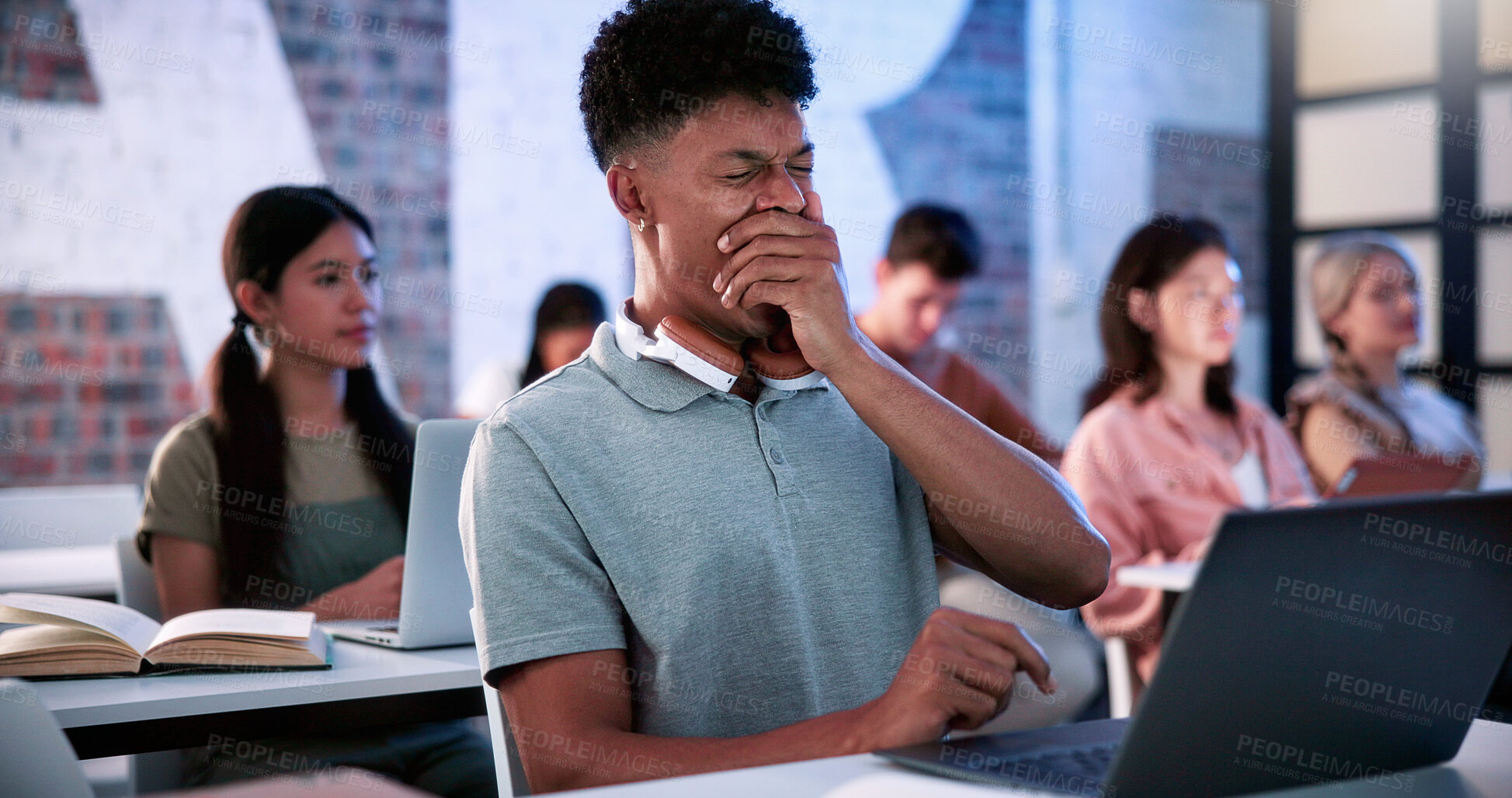 Buy stock photo University, student and yawning in classroom with laptop, education or fatigue from academic exams. Tired, man and overworked in study hall with pc, learning lecture and burnout of college assessment