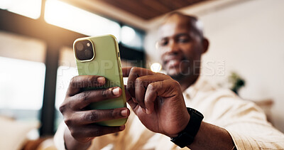 Buy stock photo Hands, phone and man in home with internet connection for social media, messaging app and search. Black person, technology and scroll online in lounge to relax, networking and notification on sofa