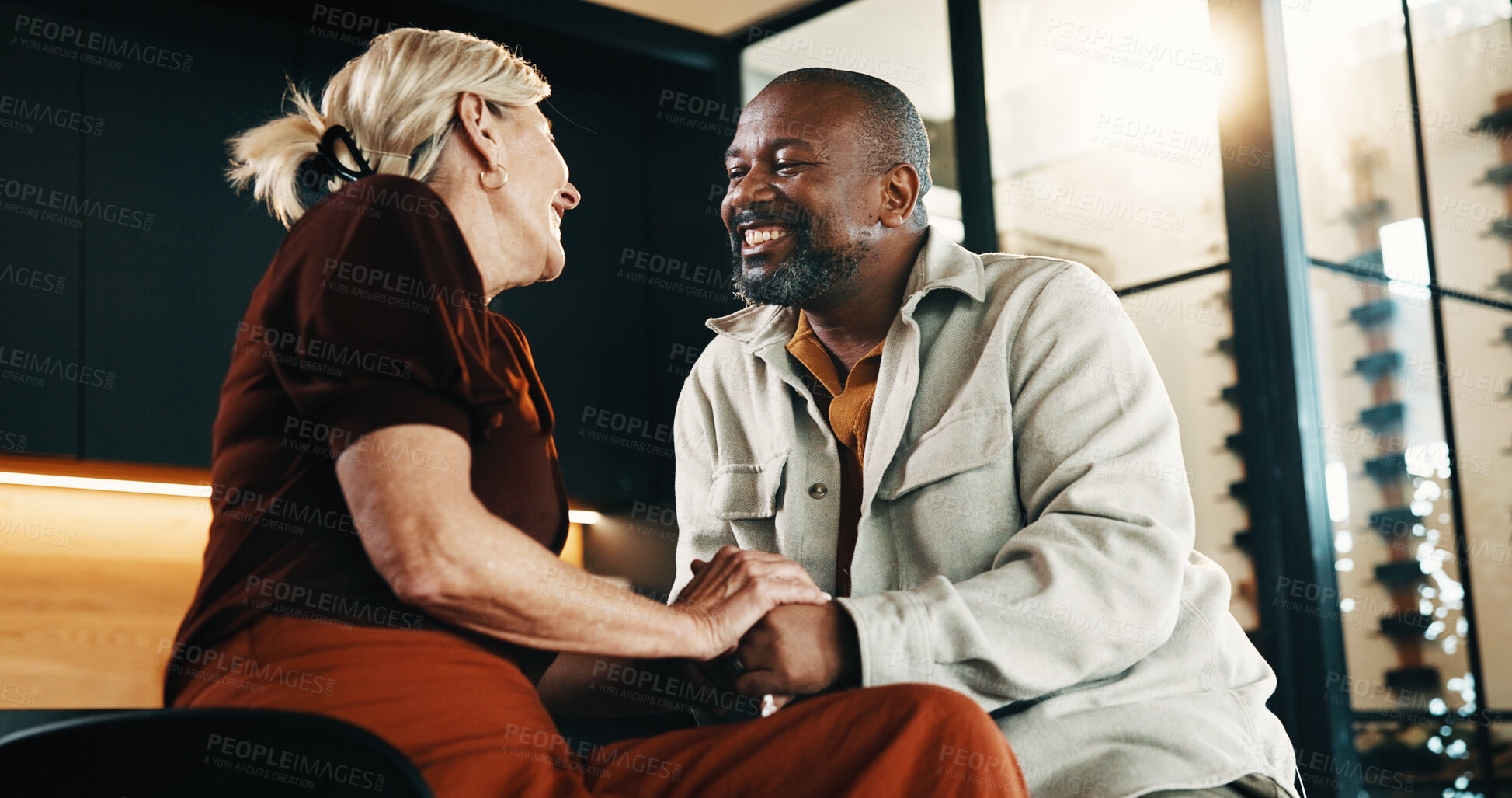 Buy stock photo Holding hands, love and smile with interracial couple in home living room for bonding or security. Affection, happy and relax with mature people on sofa in apartment for support, trust or wellness