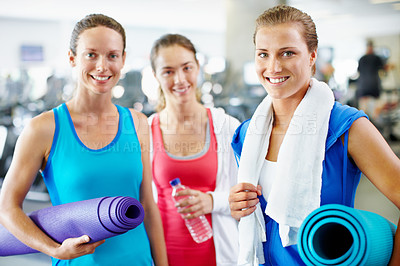 Buy stock photo Portrait of three young women with yoga mats standing in a gym