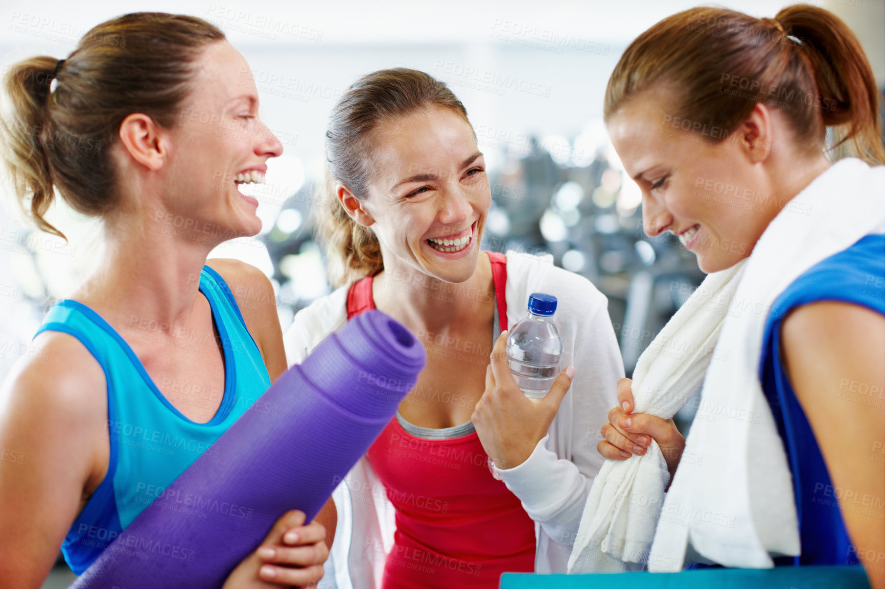 Buy stock photo Shot of three young women with yoga mats talking in a gym