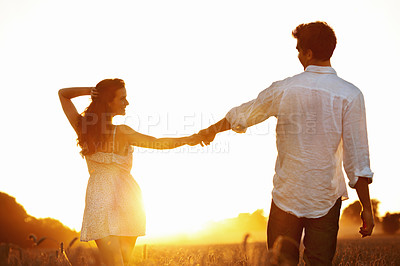 Buy stock photo Holding hands, sunset and love with couple in field for honeymoon getaway, support and trust. Care, connection and date with man and woman in countryside for loyalty, holiday and travel together