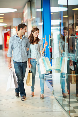 Buy stock photo Couple, window shopping and laughing with bags in mall, walk or sale choice with partner on weekend. Boutique, glass and happy people with purchase decision, bonding and plan with customer discount